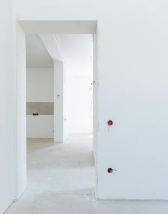 Bright unfinished room with white walls and exposed wiring, showcasing modern interior design potential.